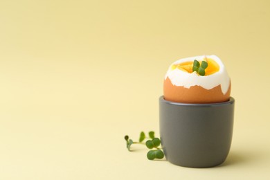 Photo of Soft boiled egg in eggcup on beige background, closeup. Space for text