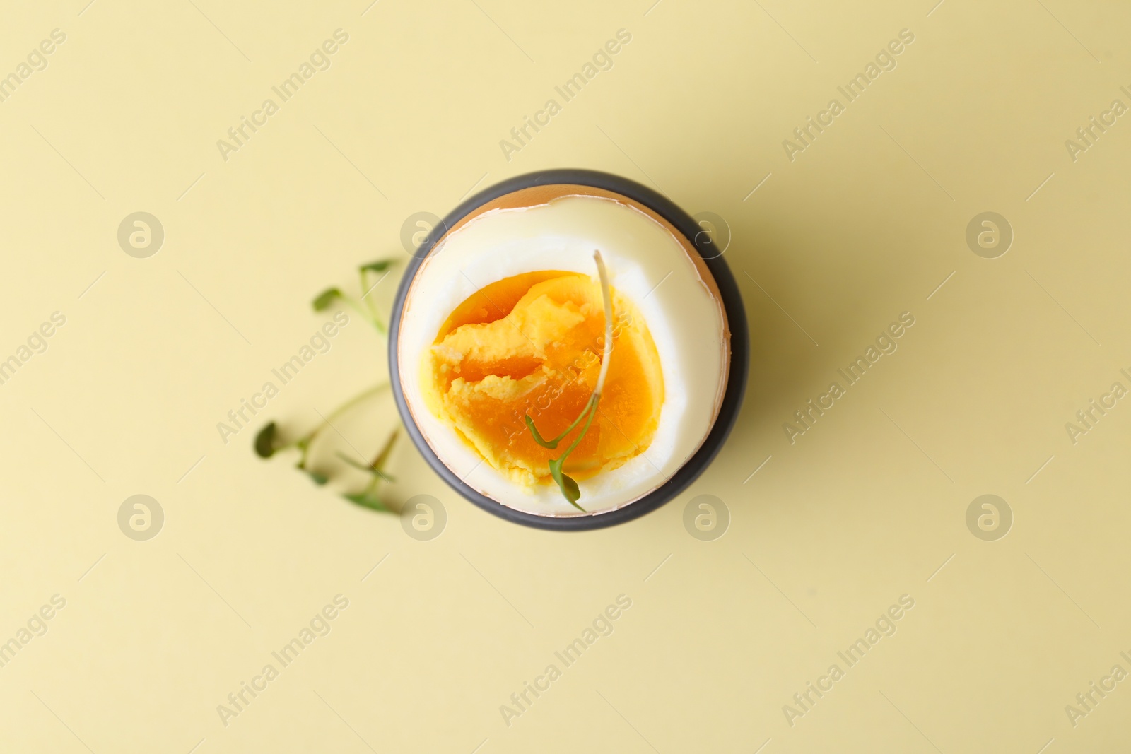 Photo of Soft boiled egg in eggcup on beige background, top view