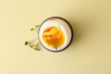 Soft boiled egg in eggcup on beige background, top view