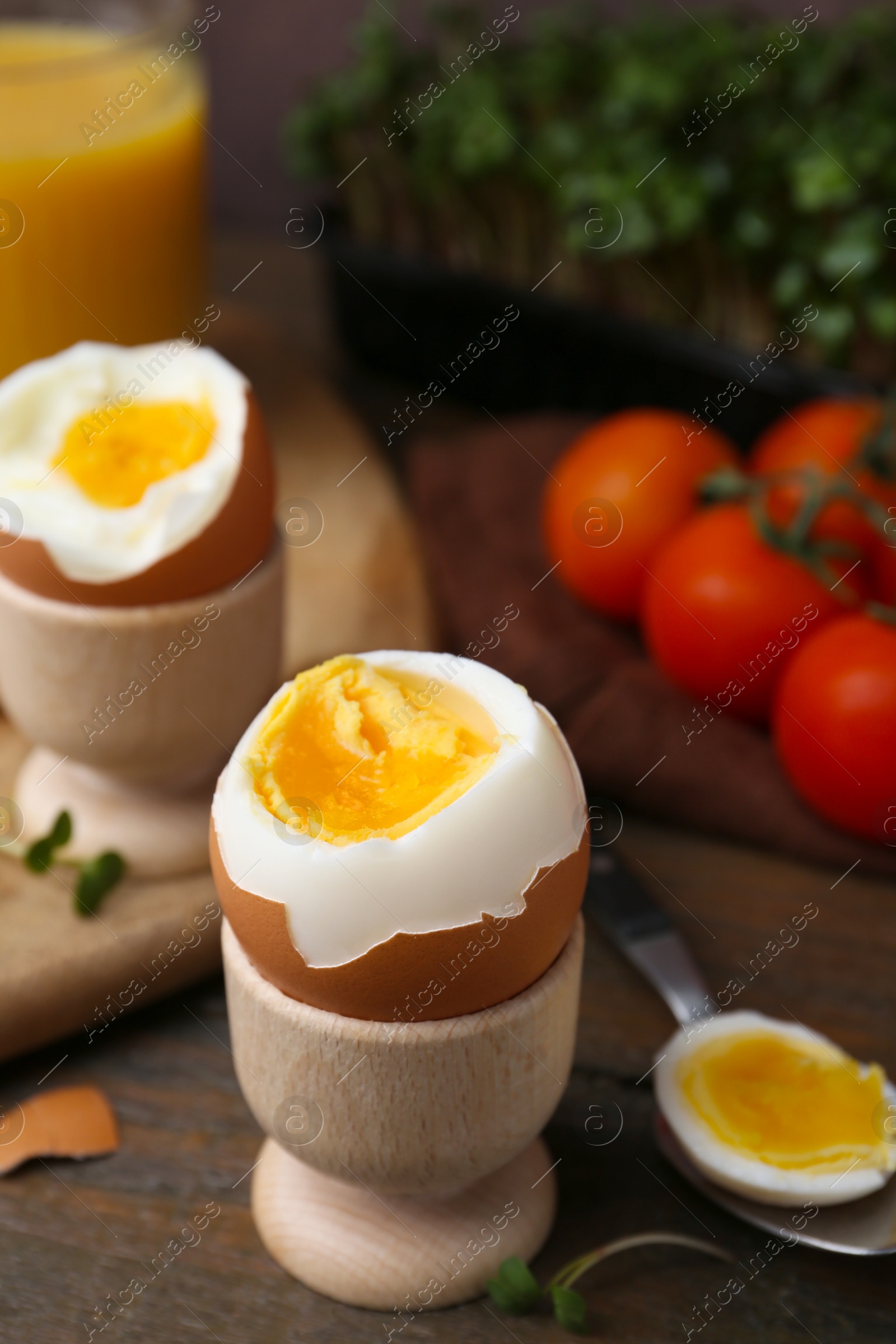 Photo of Soft boiled eggs, microgreens and tomatoes on wooden table, selective focus