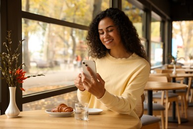 Photo of Woman using smartphone during her coffee break in cafe