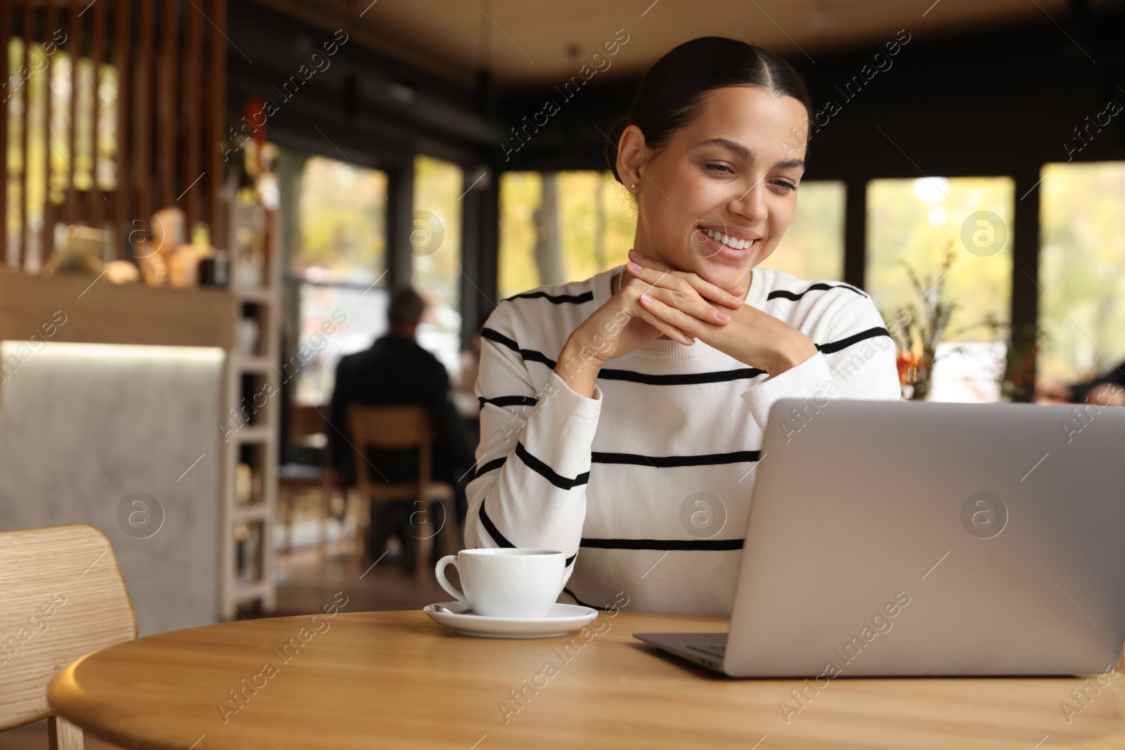 Photo of Woman working on laptop at table in cafe