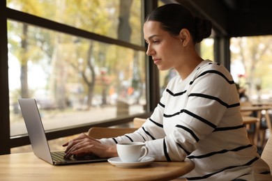 Woman working on laptop at table in cafe