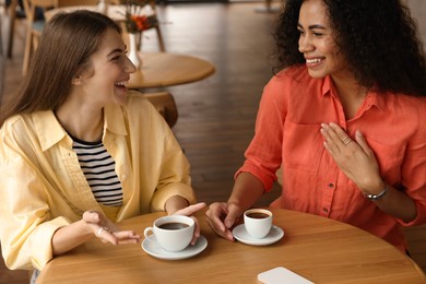 Photo of Happy women with coffee drinks chatting in cafe