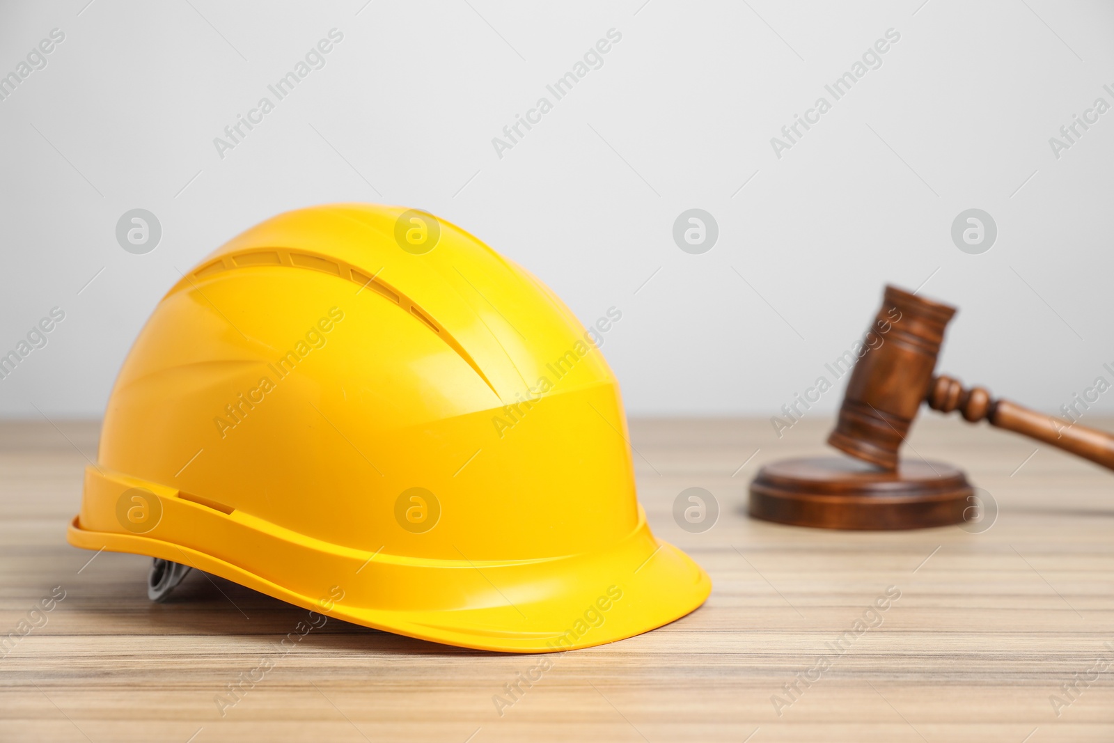 Photo of Accident at work concept. Gavel and construction worker's protective gear on wooden table, selective focus