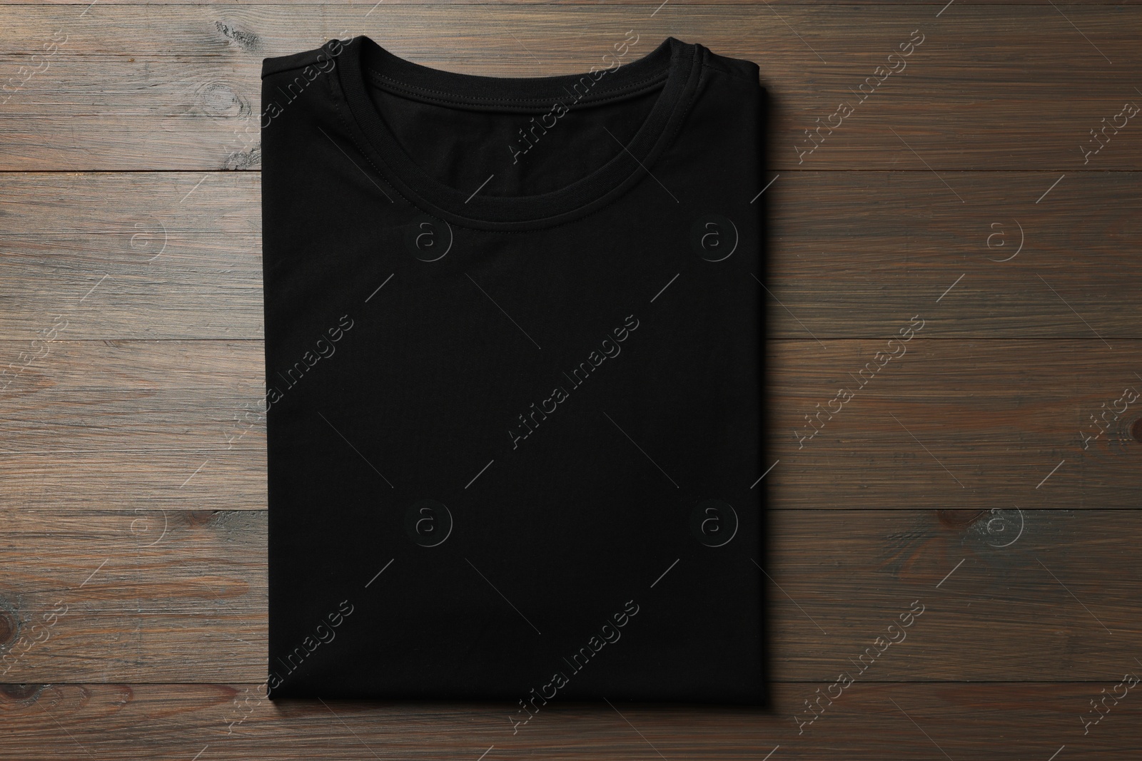 Photo of Blank black t-shirt on wooden background, top view. Mockup for design