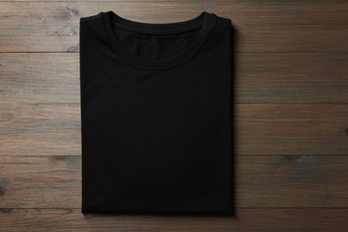 Photo of Blank black t-shirt on wooden background, top view. Mockup for design