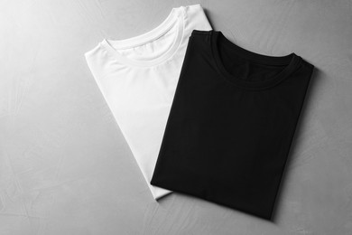 Photo of Different blank t-shirts on grey background, top view. Mockup for design