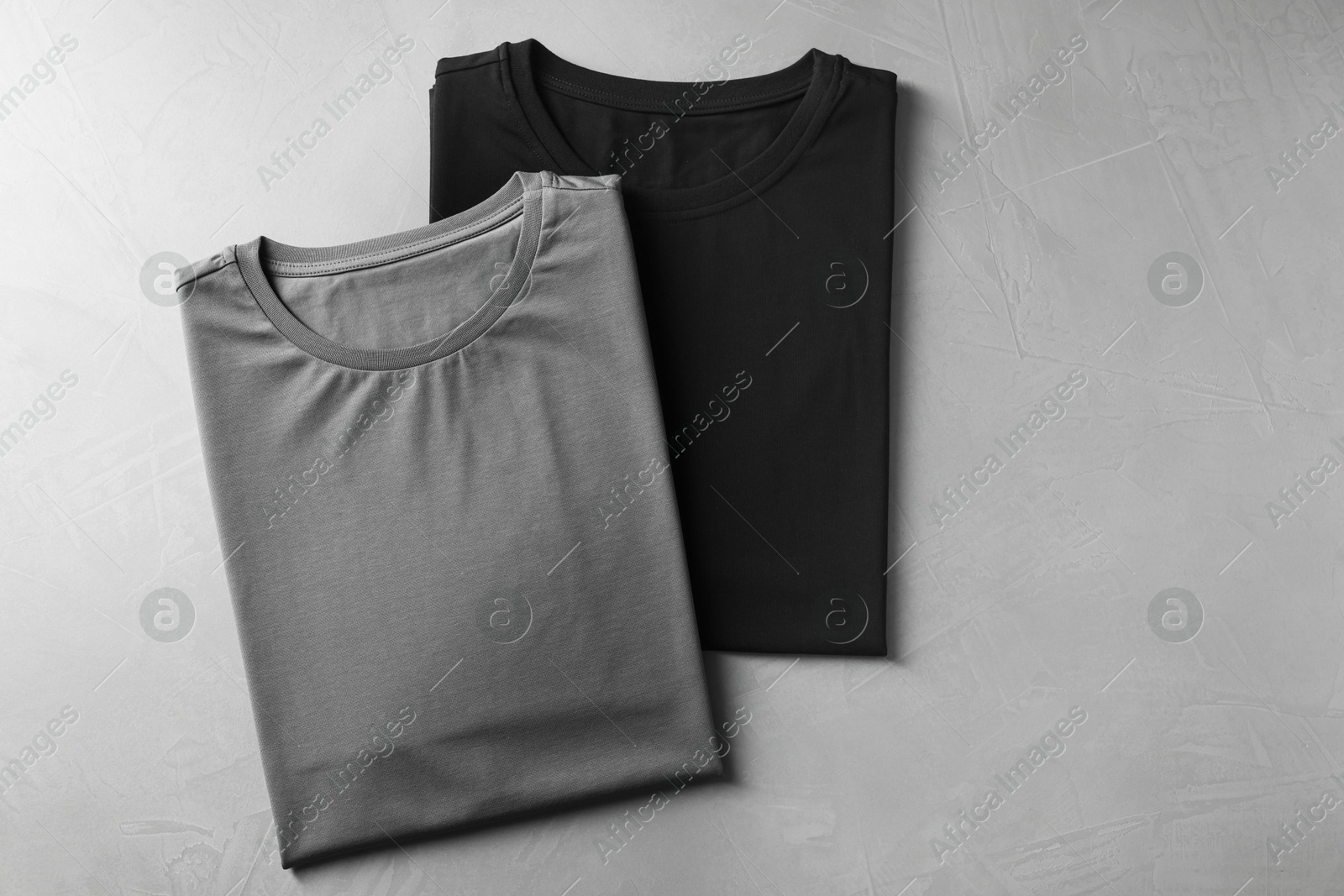 Photo of Different blank t-shirts on grey background, top view. Mockup for design