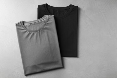 Photo of Different blank t-shirts on grey background, top view. Mockup for design