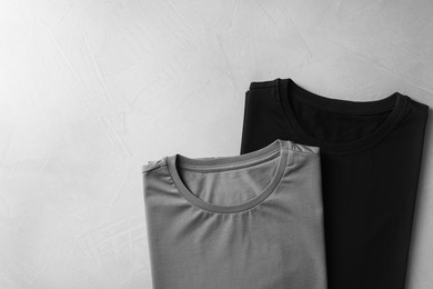 Photo of Different blank t-shirts on grey background, top view. Mockup for design