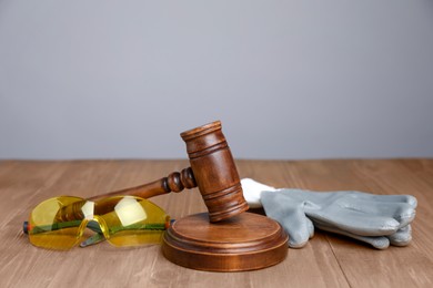 Photo of Accident at work concept. Gavel and construction worker's protective gear on wooden table