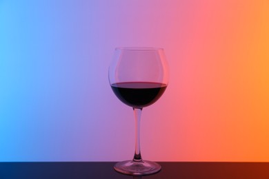 Photo of Glass of wine on table against color background