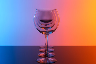 Photo of Wine glasses on table against color background