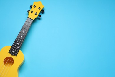 Photo of One ukulele on light blue background, top view. Space for text