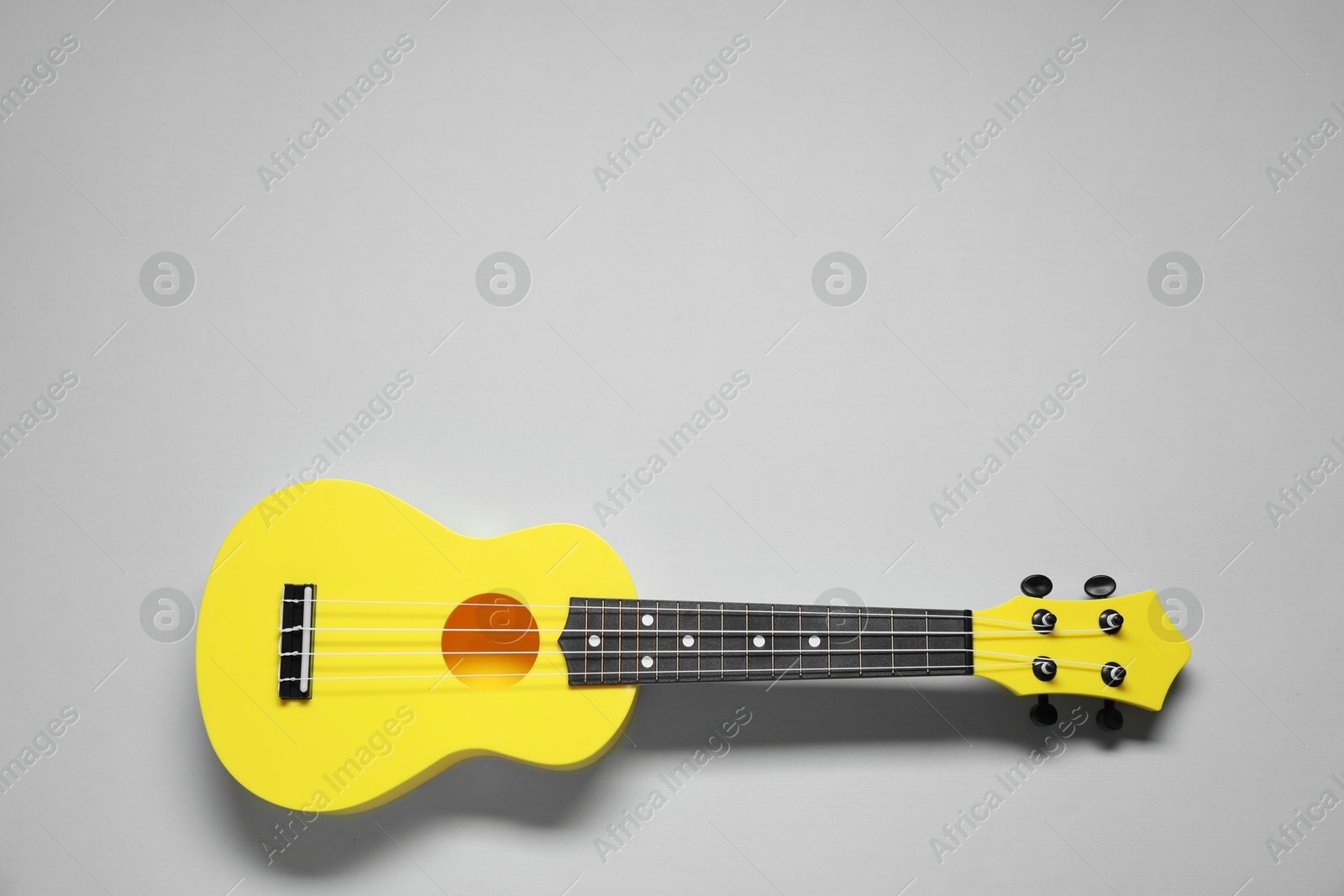 Photo of One ukulele on grey background, top view. Space for text