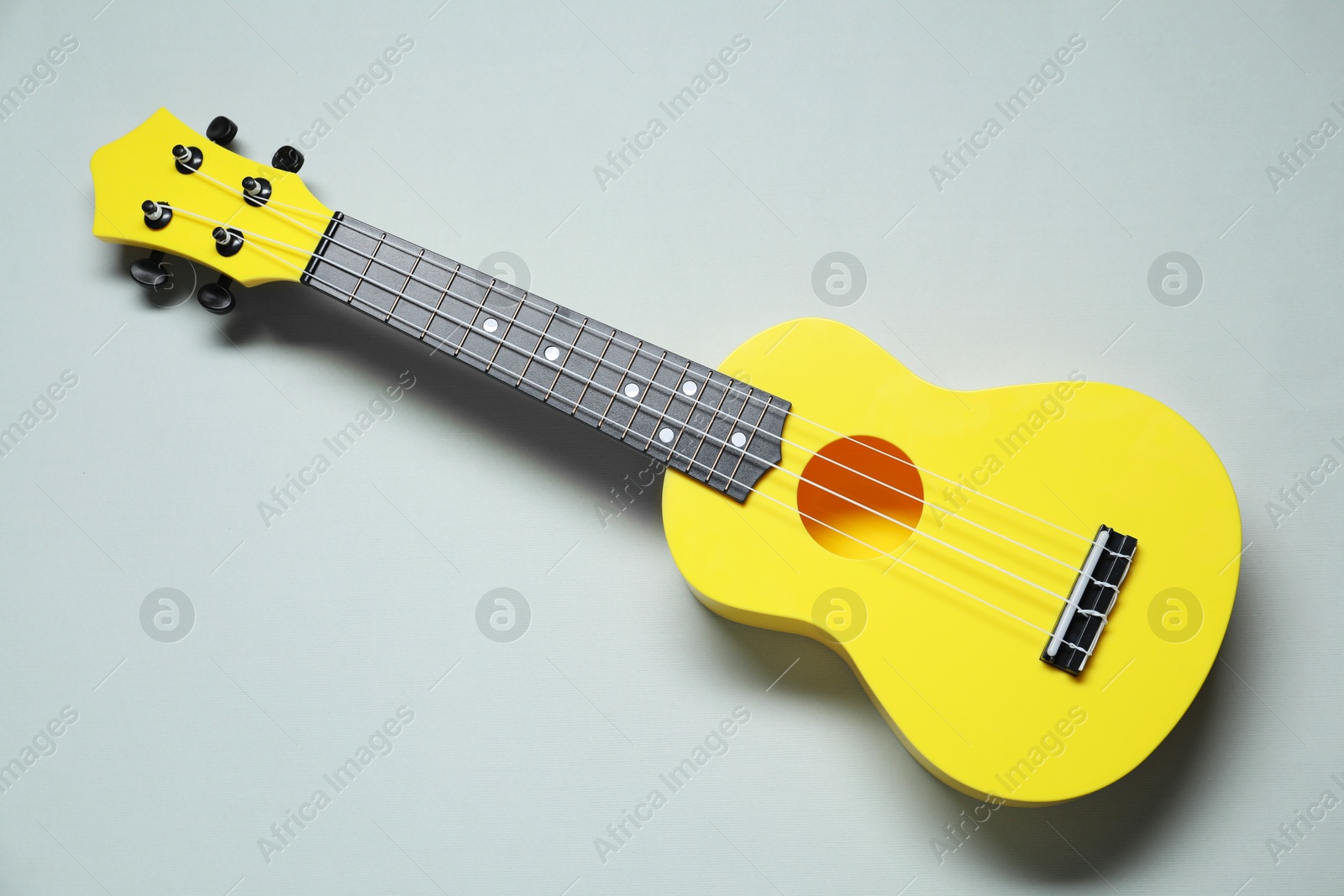 Photo of One ukulele on grey background, top view.