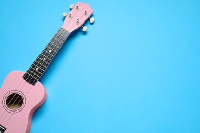 Photo of One ukulele on light blue background, top view. Space for text