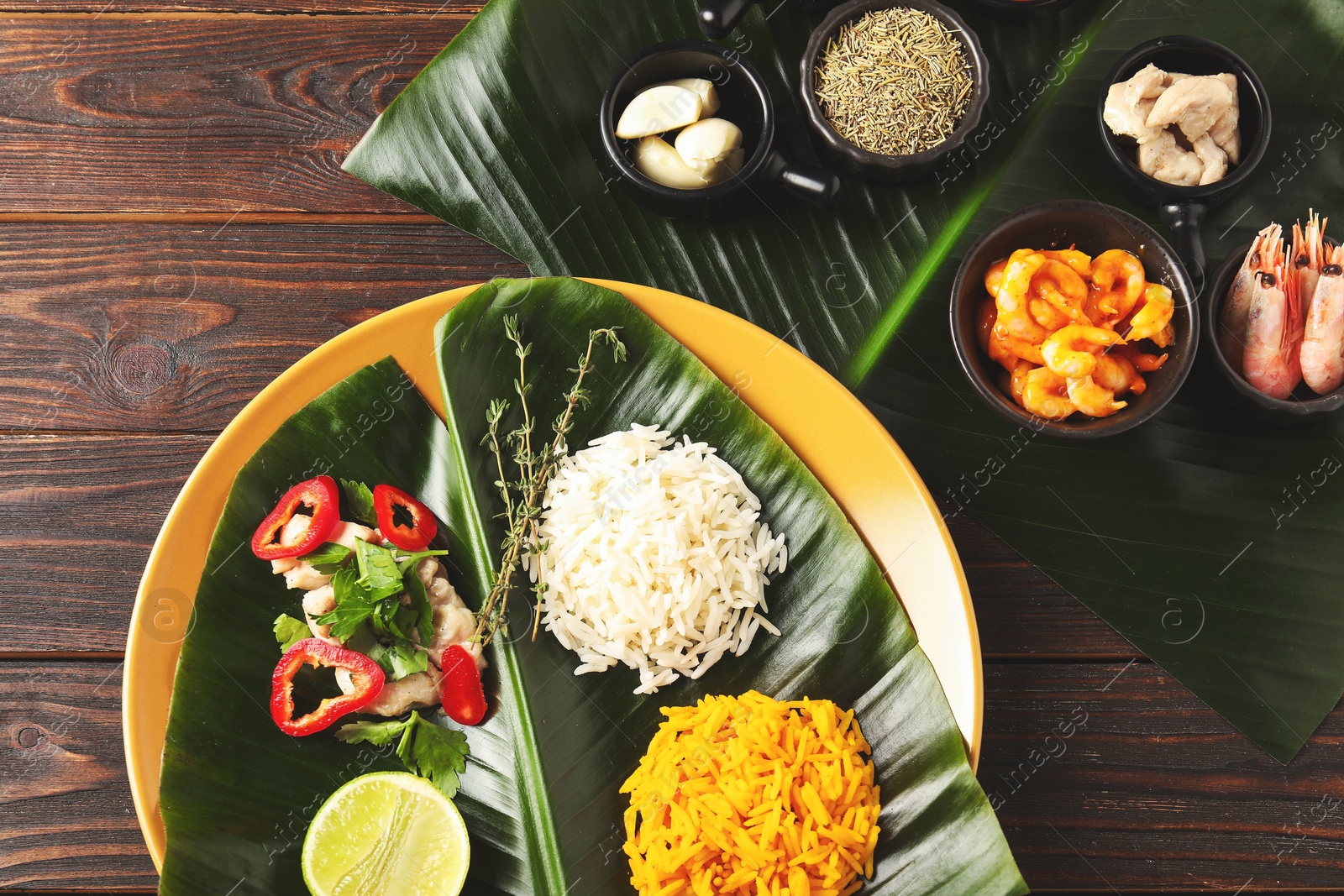 Photo of Cut banana leaves with different food and spices on wooden table, flat lay