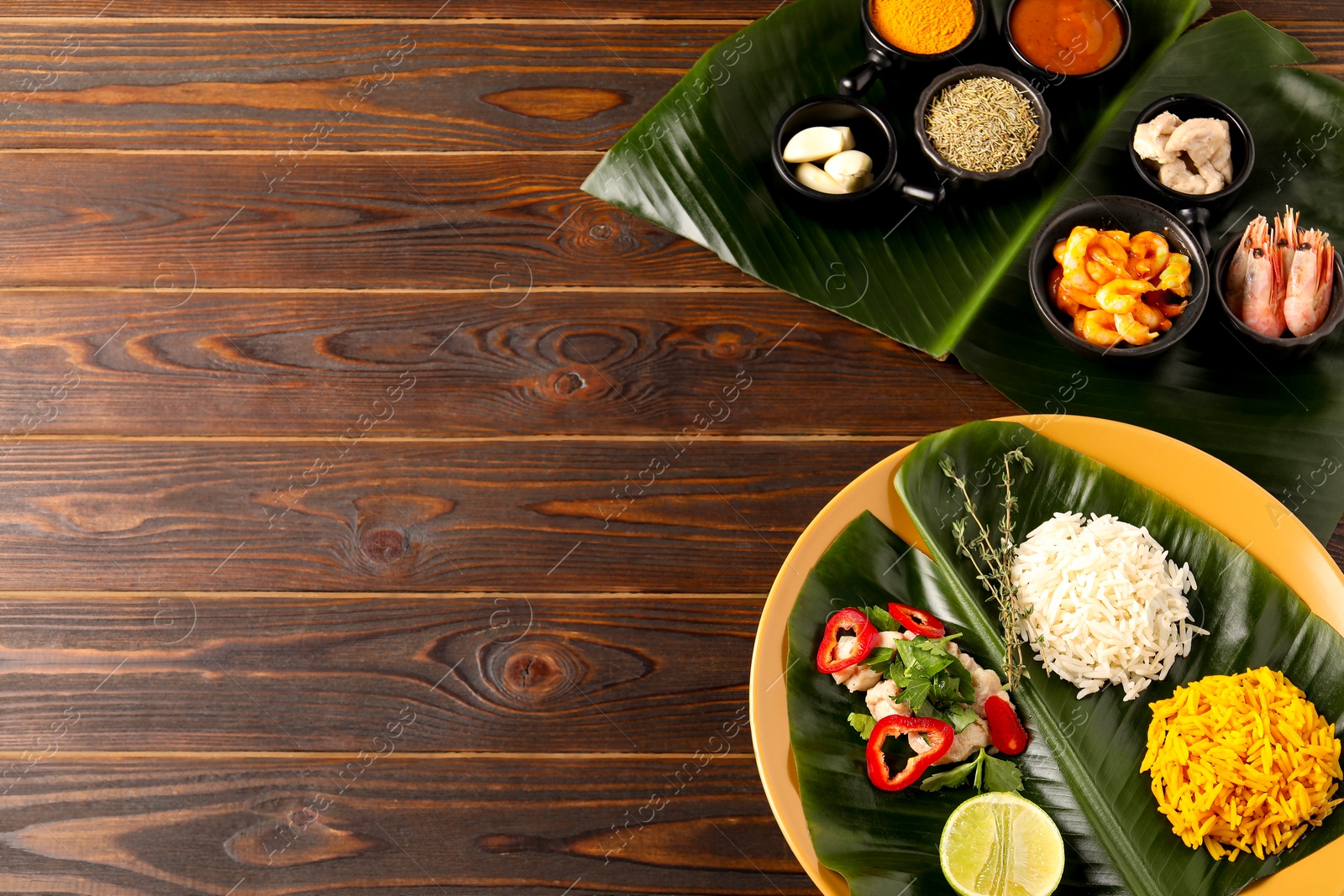 Photo of Cut banana leaves with different food, spices and sauce on wooden table, flat lay. Space for text