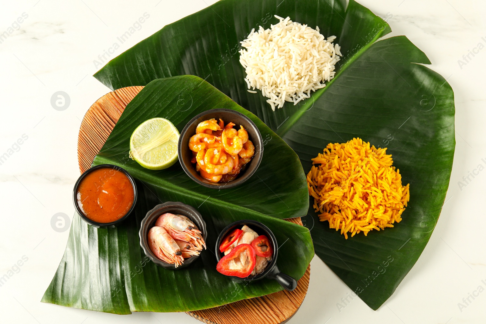 Photo of Cut banana leaves with different food and sauce on white table, flat lay