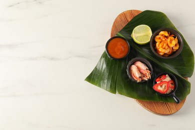 Photo of Cut banana leaf with different food and sauce on white marble table, top view. Space for text