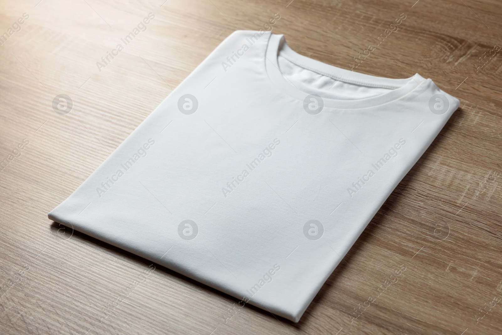 Photo of One blank t-shirt on wooden background, closeup. Mockup for design