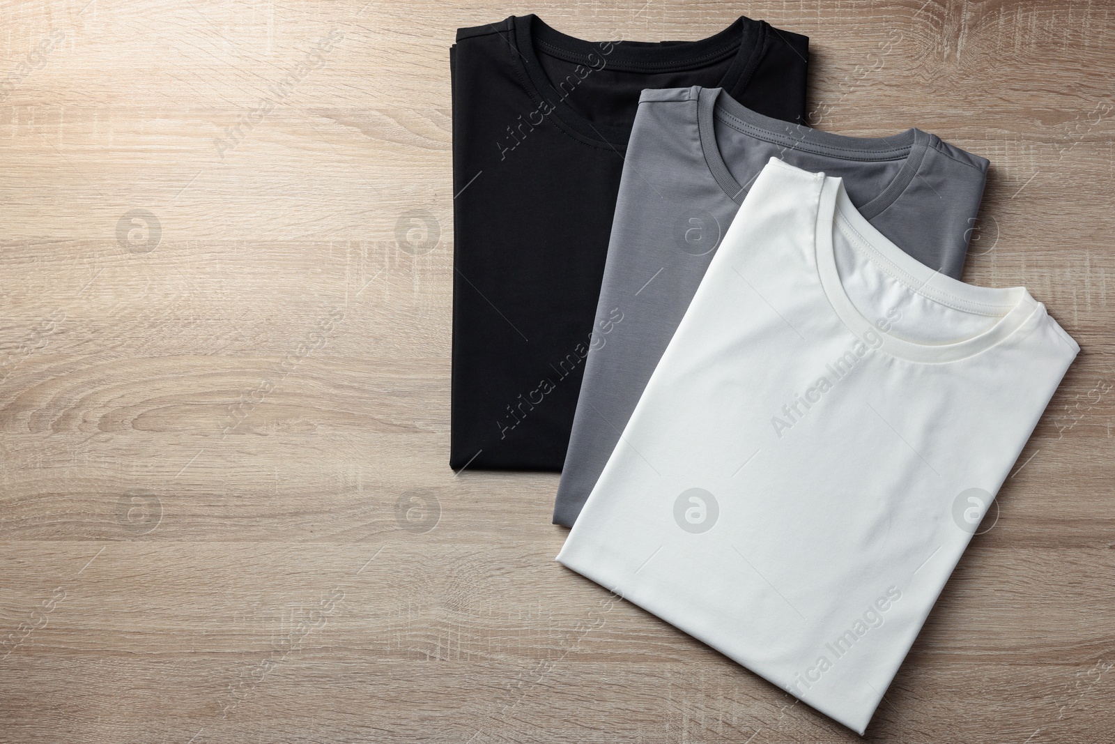 Photo of Blank t-shirts on wooden background, flat lay. Mockup for design