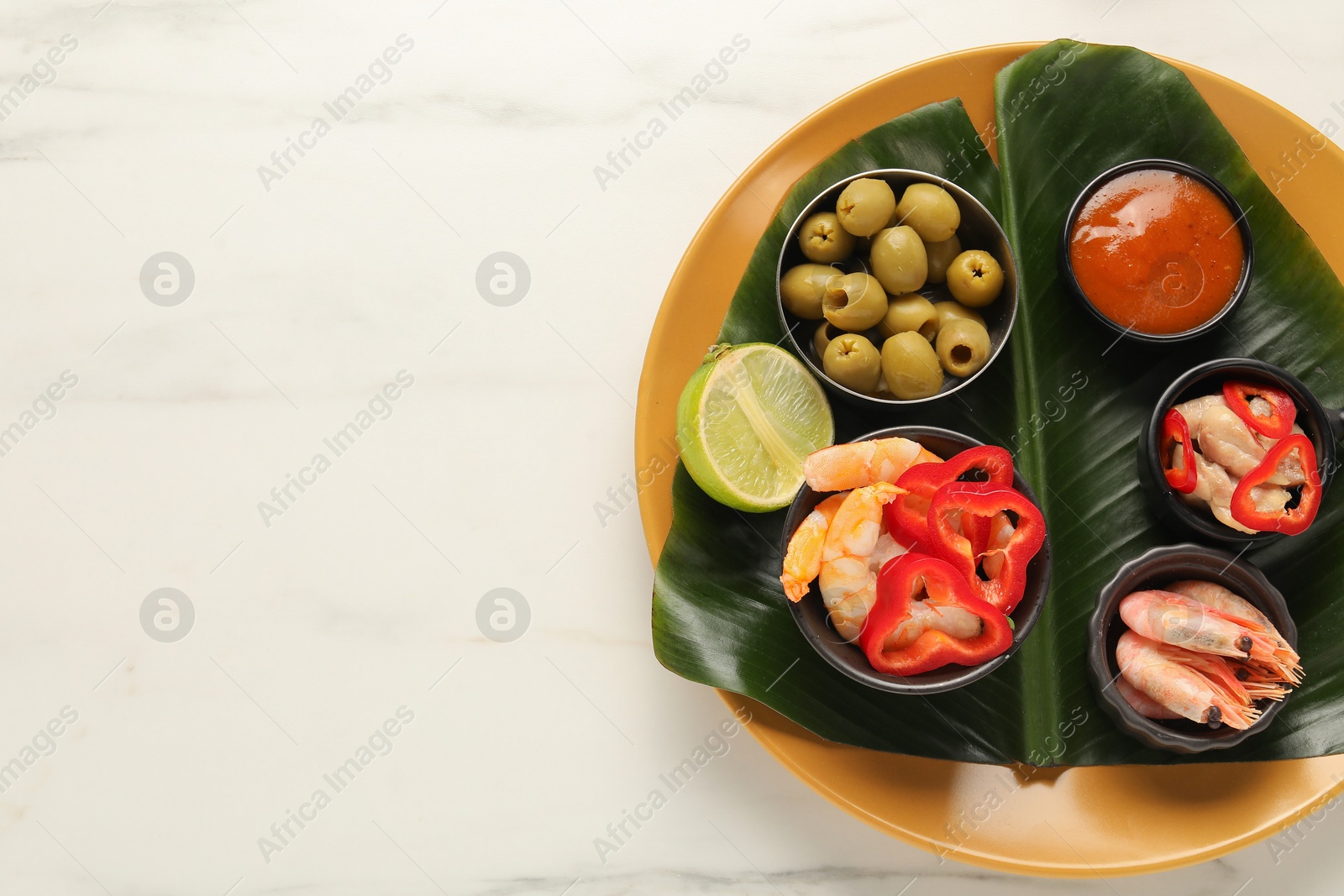 Photo of Cut banana leaf with different food and sauce on white marble table, top view. Space for text