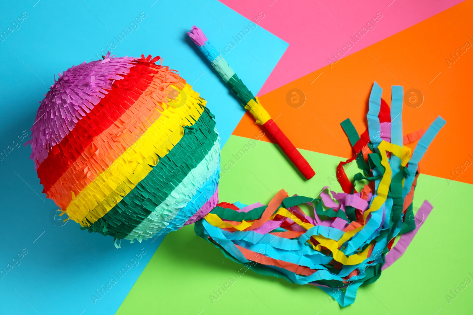 Photo of Colorful pinata and stick on color background, top view