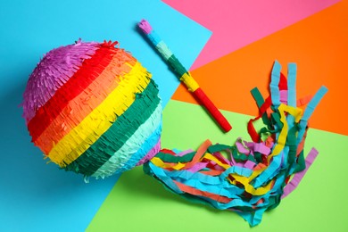 Photo of Colorful pinata and stick on color background, top view