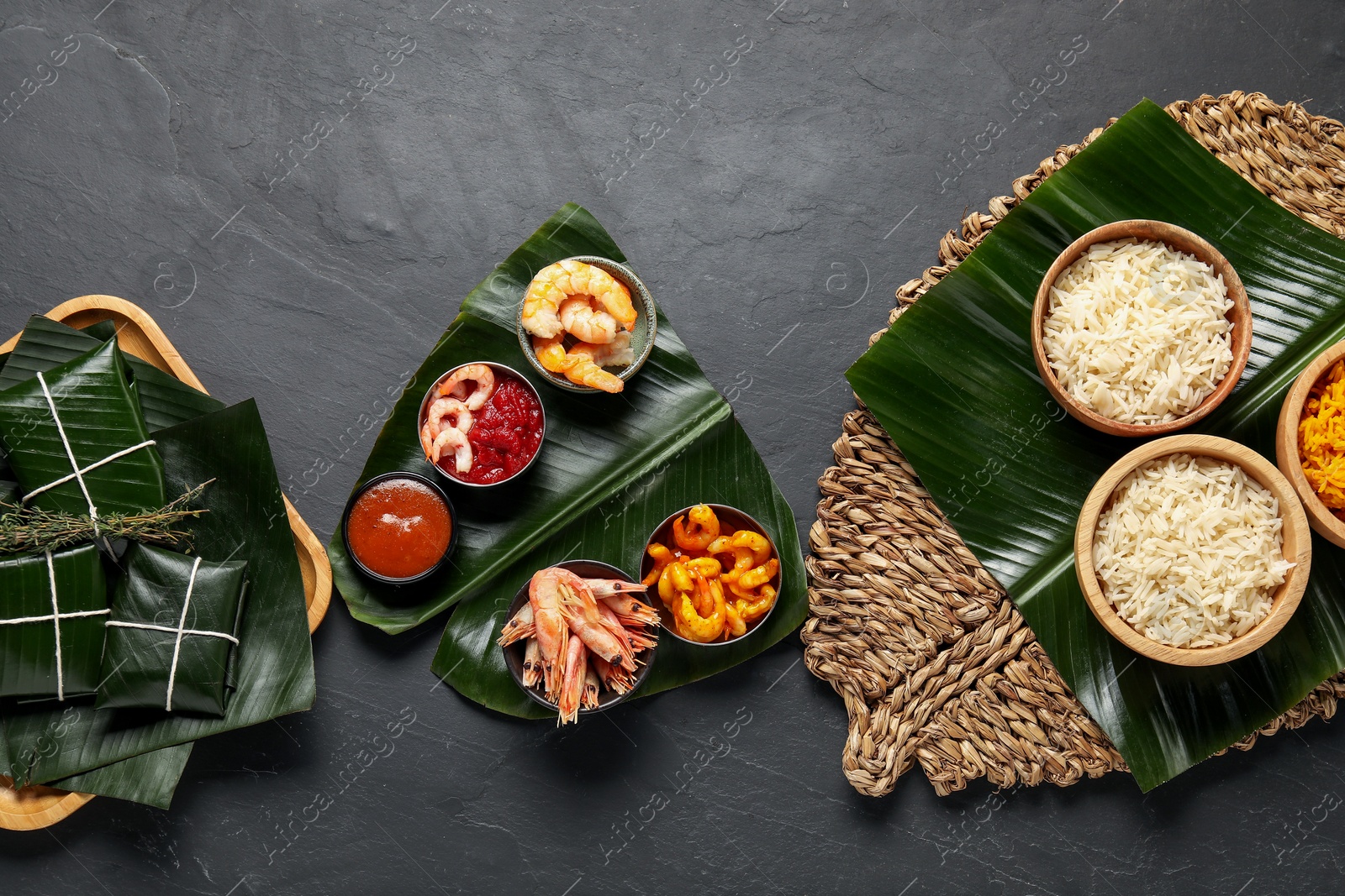 Photo of Cut banana leaves with different food, spices and sauce on dark textured table, flat lay. Healthy eco serving