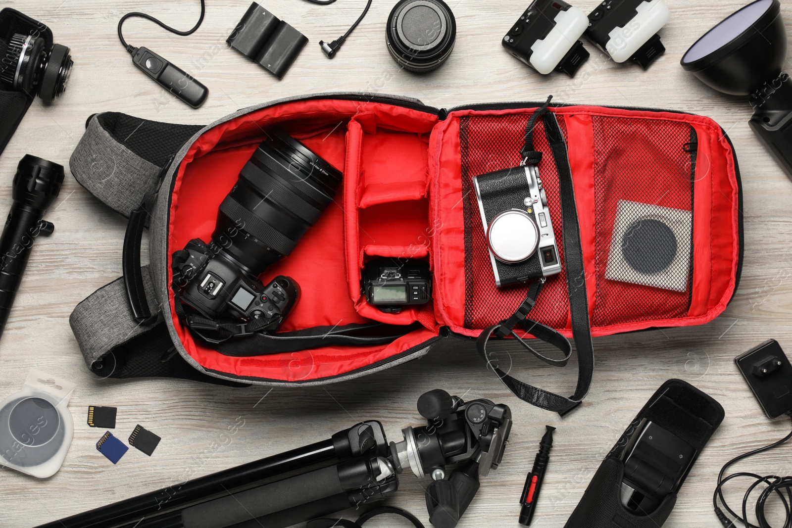 Photo of Professional photographer's equipment and backpack on light wooden background, flat lay