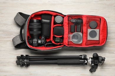 Photo of Professional photographer's equipment and backpack on light wooden background, flat lay