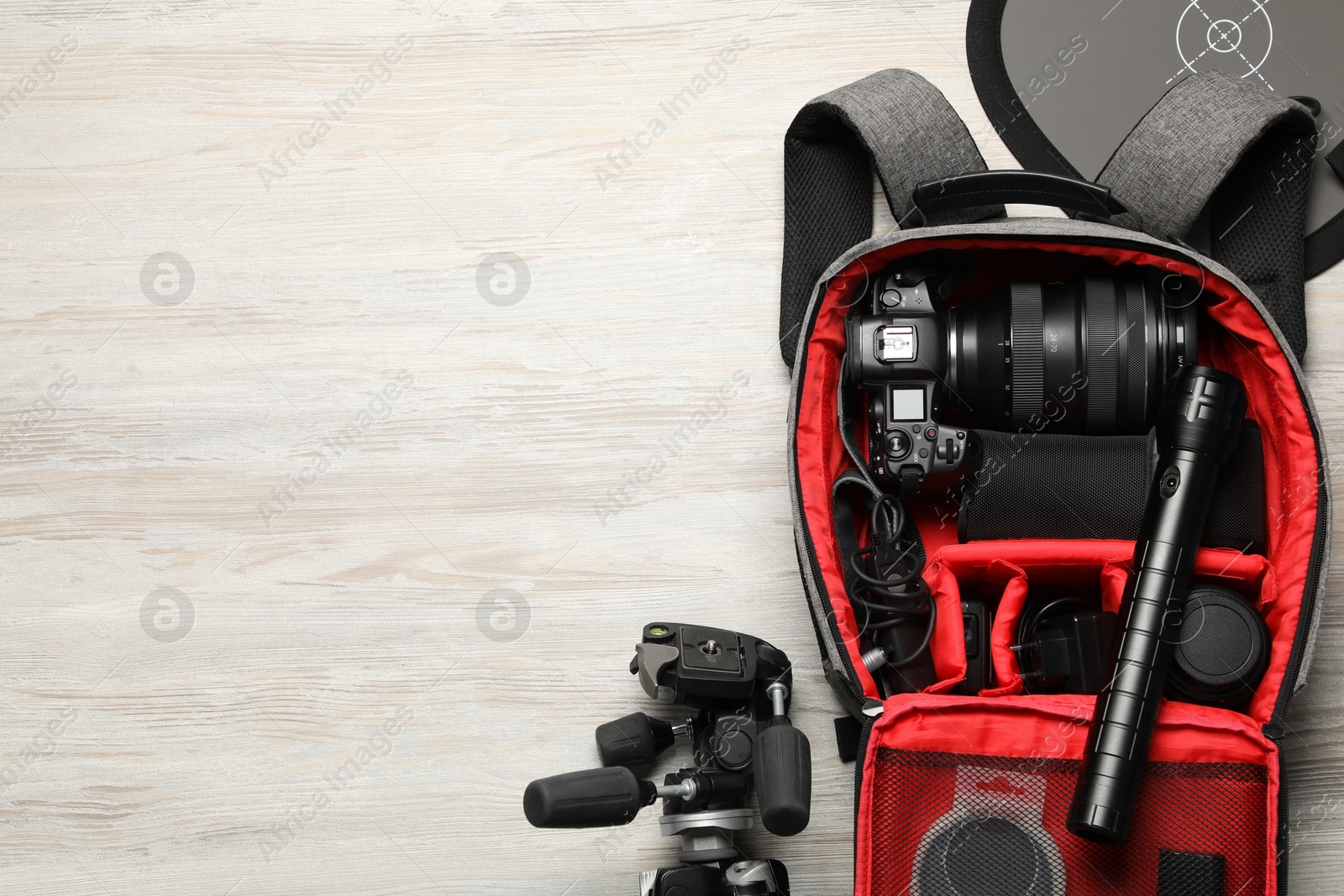 Photo of Professional photographer's equipment and backpack on light wooden background, flat lay. Space for text