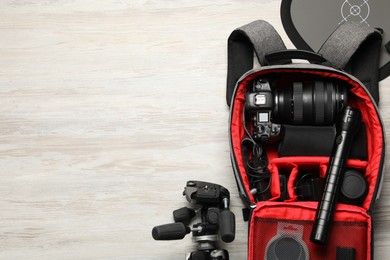 Photo of Professional photographer's equipment and backpack on light wooden background, flat lay. Space for text