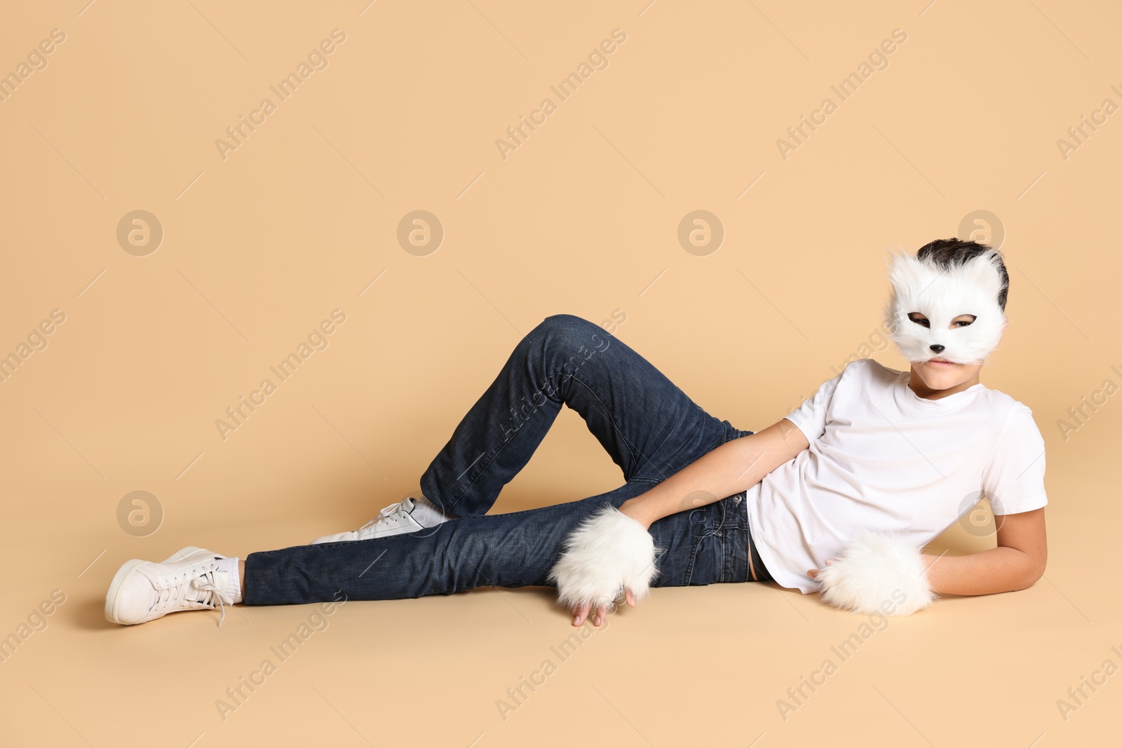 Photo of Quadrobics. Boy wearing cat mask and gloves on beige background