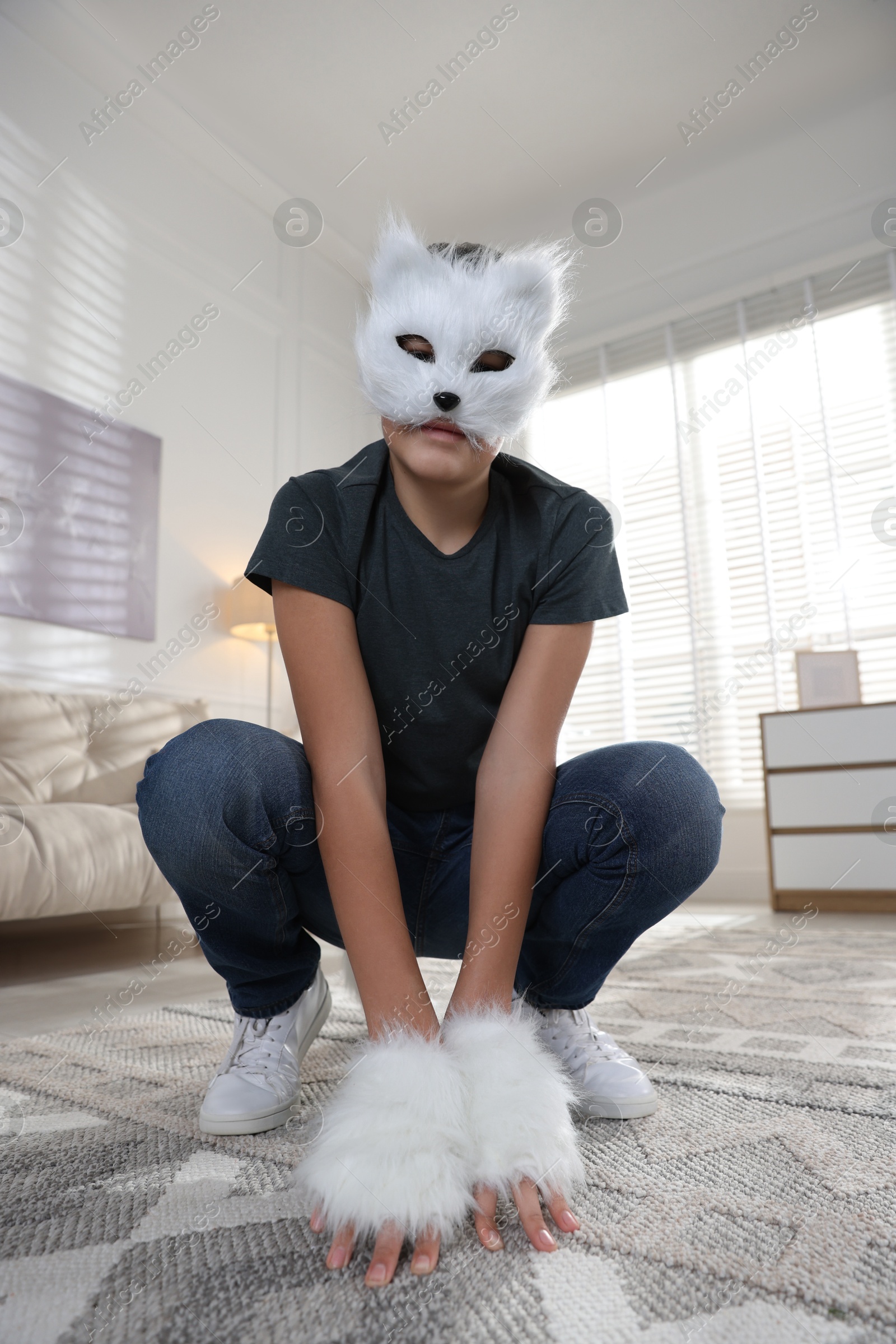 Photo of Quadrobics. Boy wearing cat mask and gloves at home