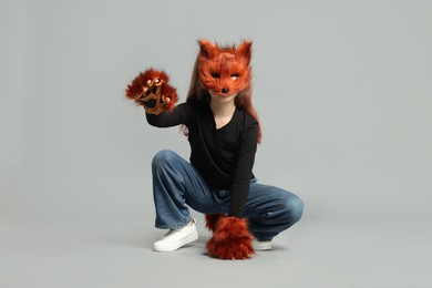 Photo of Quadrobics. Girl wearing fox mask and gloves on grey background