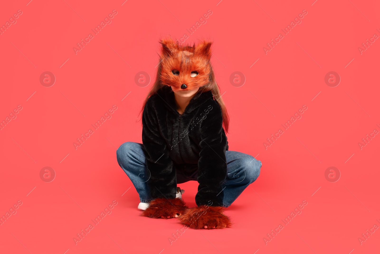 Photo of Quadrobics. Girl wearing fox mask and gloves on red background