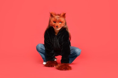 Photo of Quadrobics. Girl wearing fox mask and gloves on red background