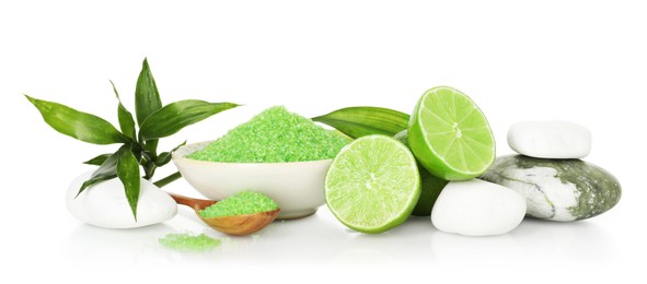 Photo of Spa composition with fresh limes, sea salt, massage stones and bamboo leaves on mirror surface against white background