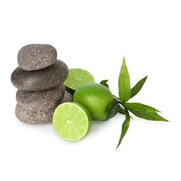 Photo of Spa composition with fresh limes, stack of pebble stones and bamboo leaves isolated on white