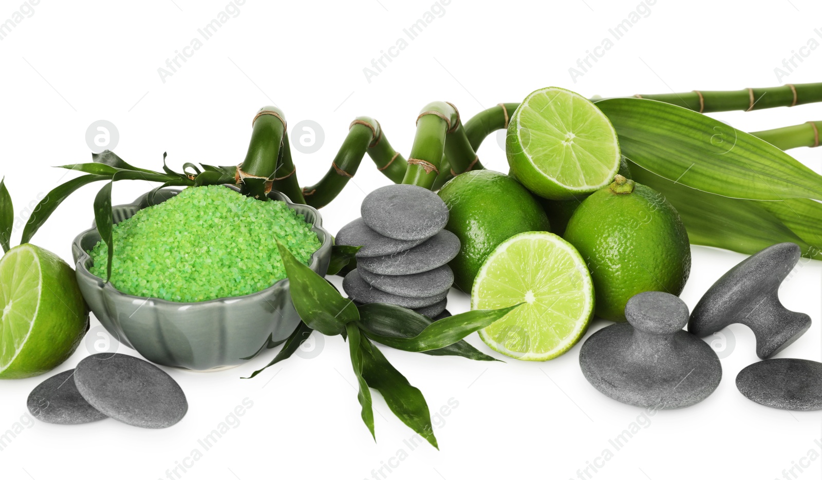 Spa composition with fresh limes, sea salt, massage stones and bamboo isolated on white Photo of Spa composition with fresh limes, sea salt, massage stones and bamboo isolated on white