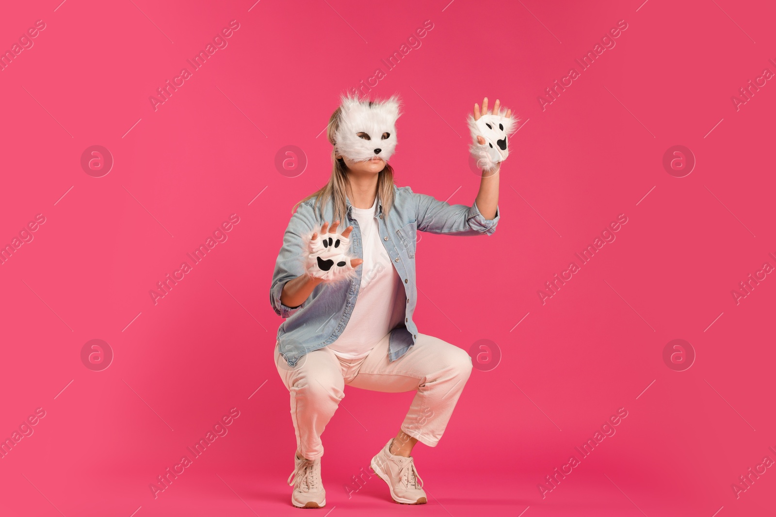 Photo of Quadrobics. Woman wearing cat mask and gloves on pink background