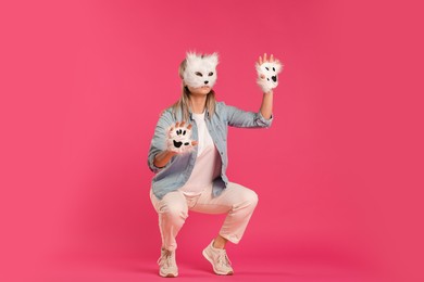 Photo of Quadrobics. Woman wearing cat mask and gloves on pink background