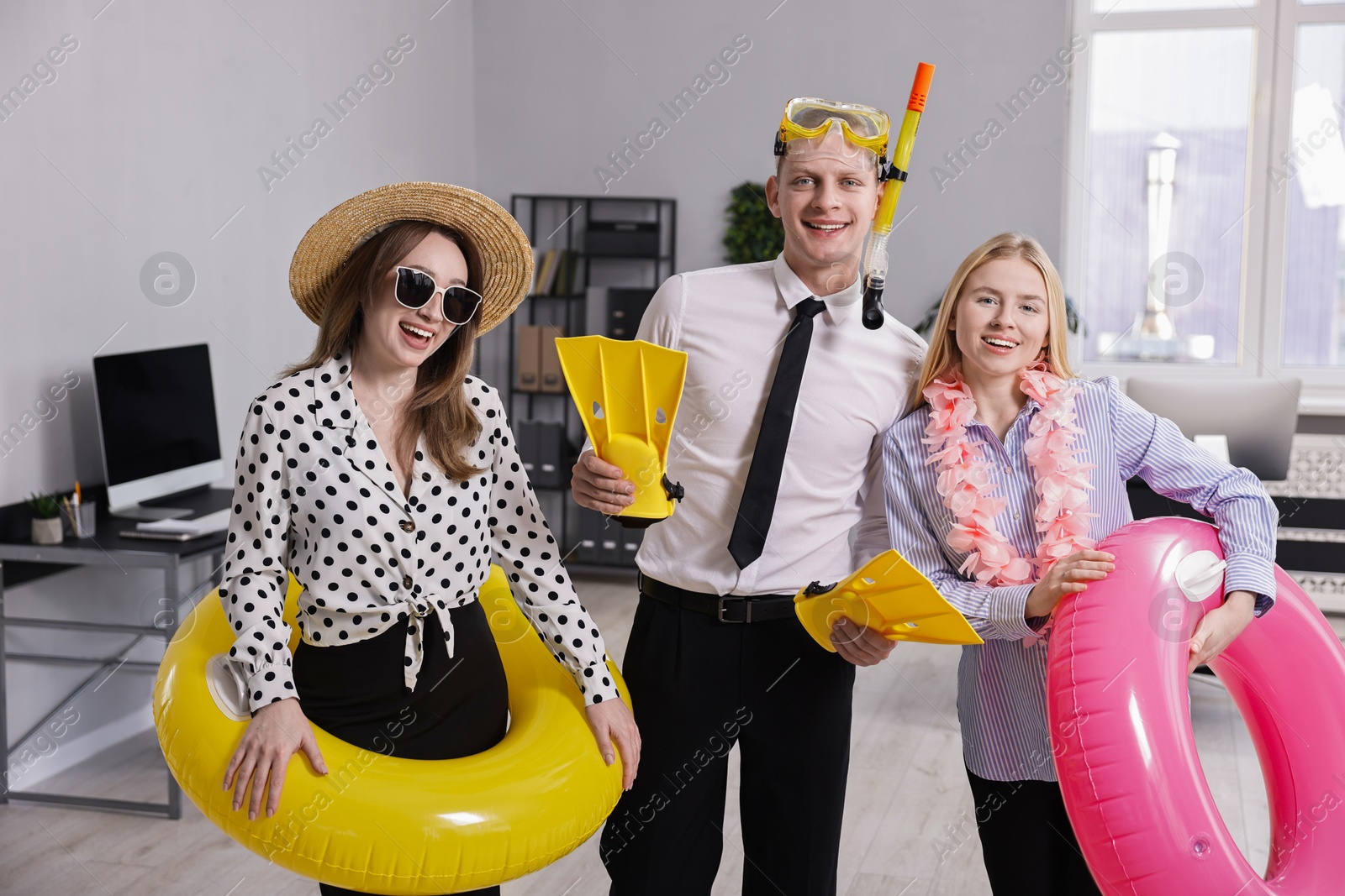 Photo of Colleagues with different beach accessories having fun in office