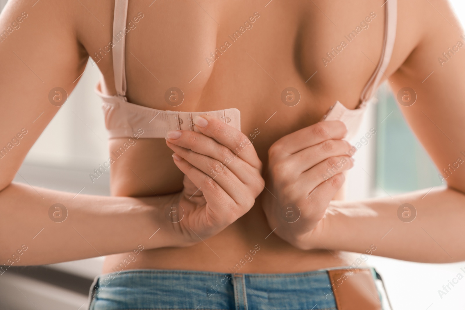 Photo of Woman putting on comfortable bra indoors, closeup