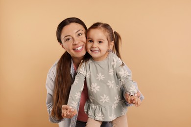 Photo of Portrait of happy mother and her cute little daughter on beige background