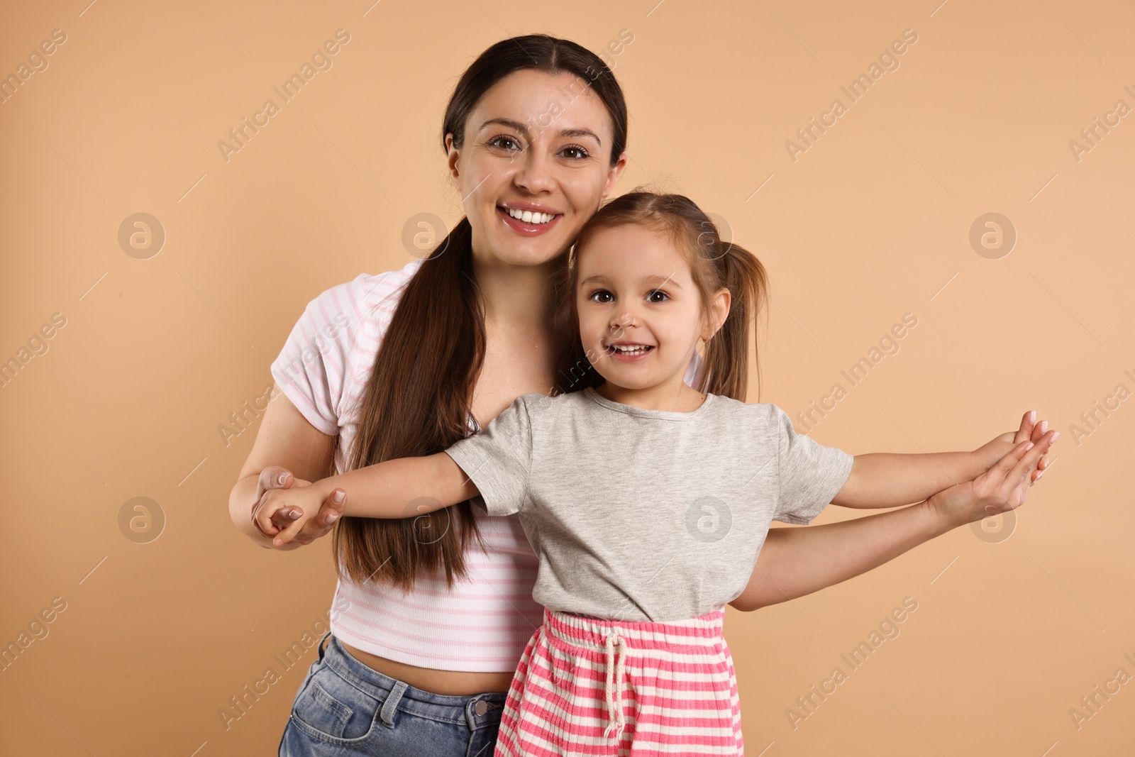 Photo of Portrait of happy mother and her cute little daughter on beige background